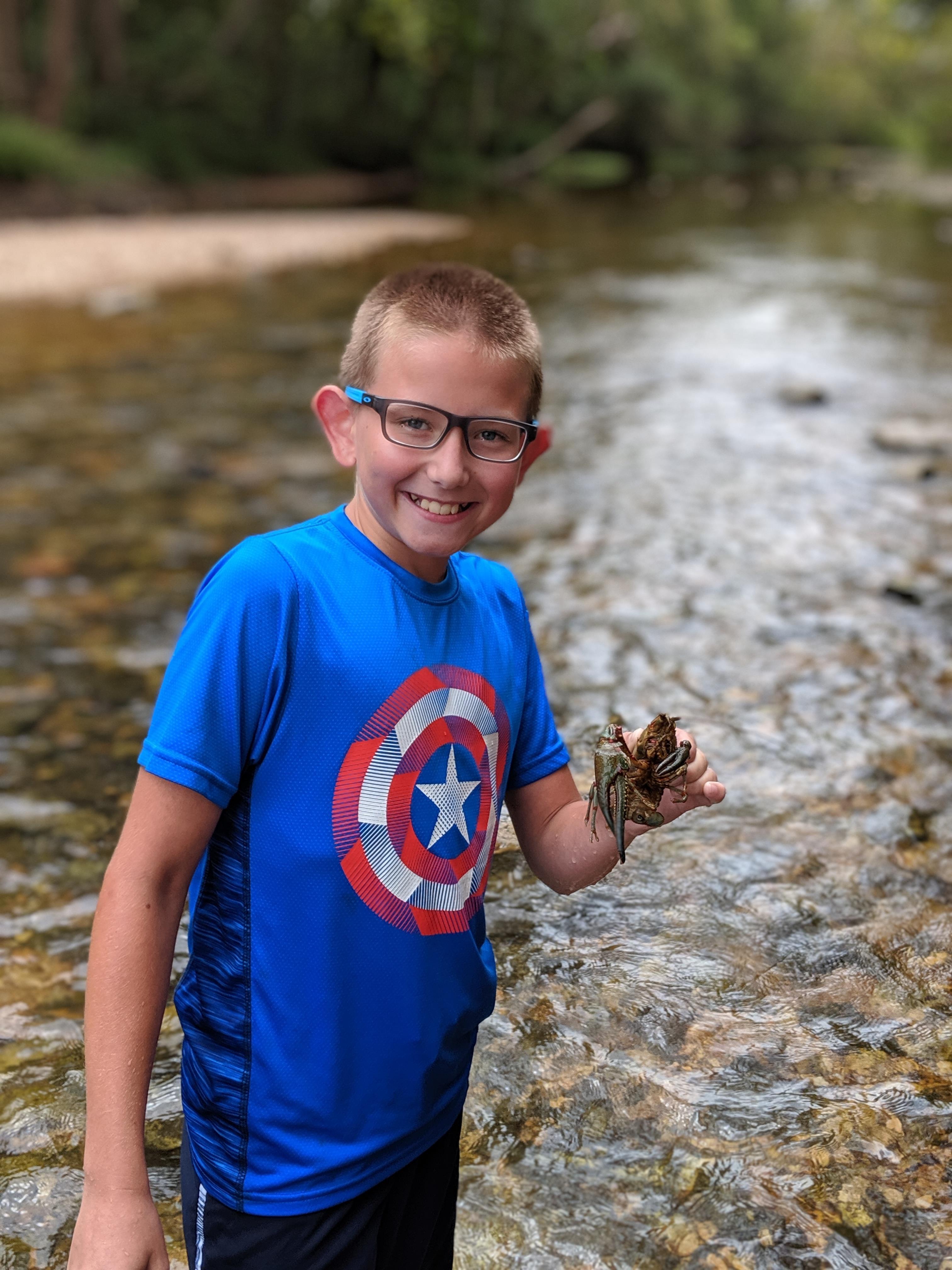 Young boy in stream with macroinvertebrate