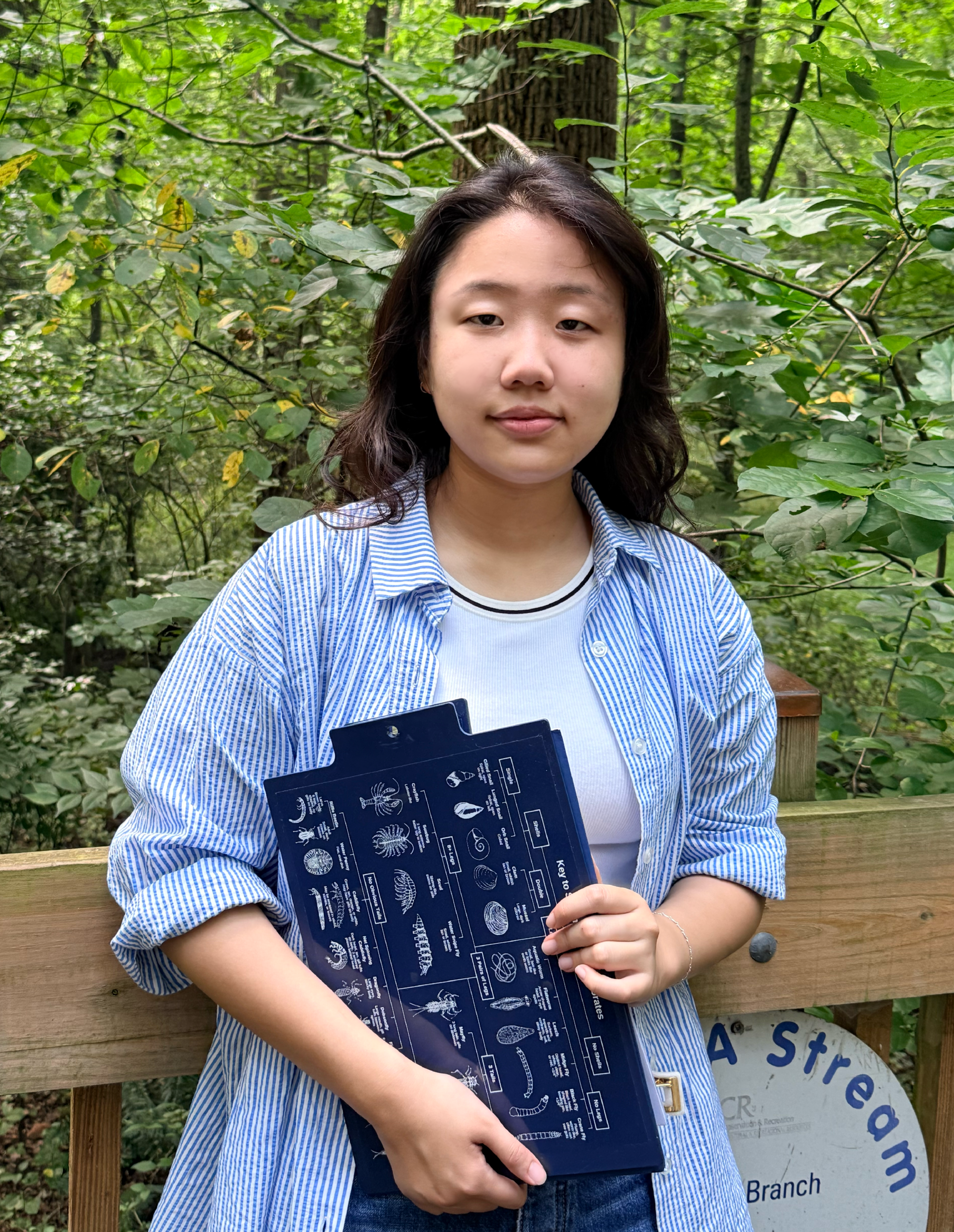 Jiwoo poses with a Save Our Streams dichotomous key clipboard.